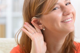 Lady holding hearing aid behind ear